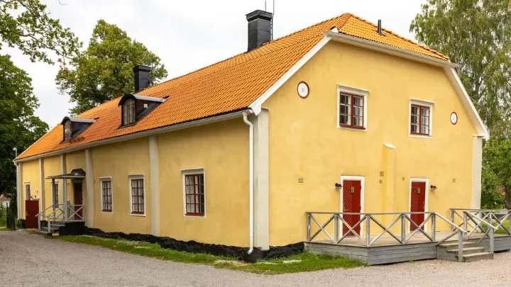 Der Flügel Paradiset mit gelber Holzfassade und weißen Fenstern.