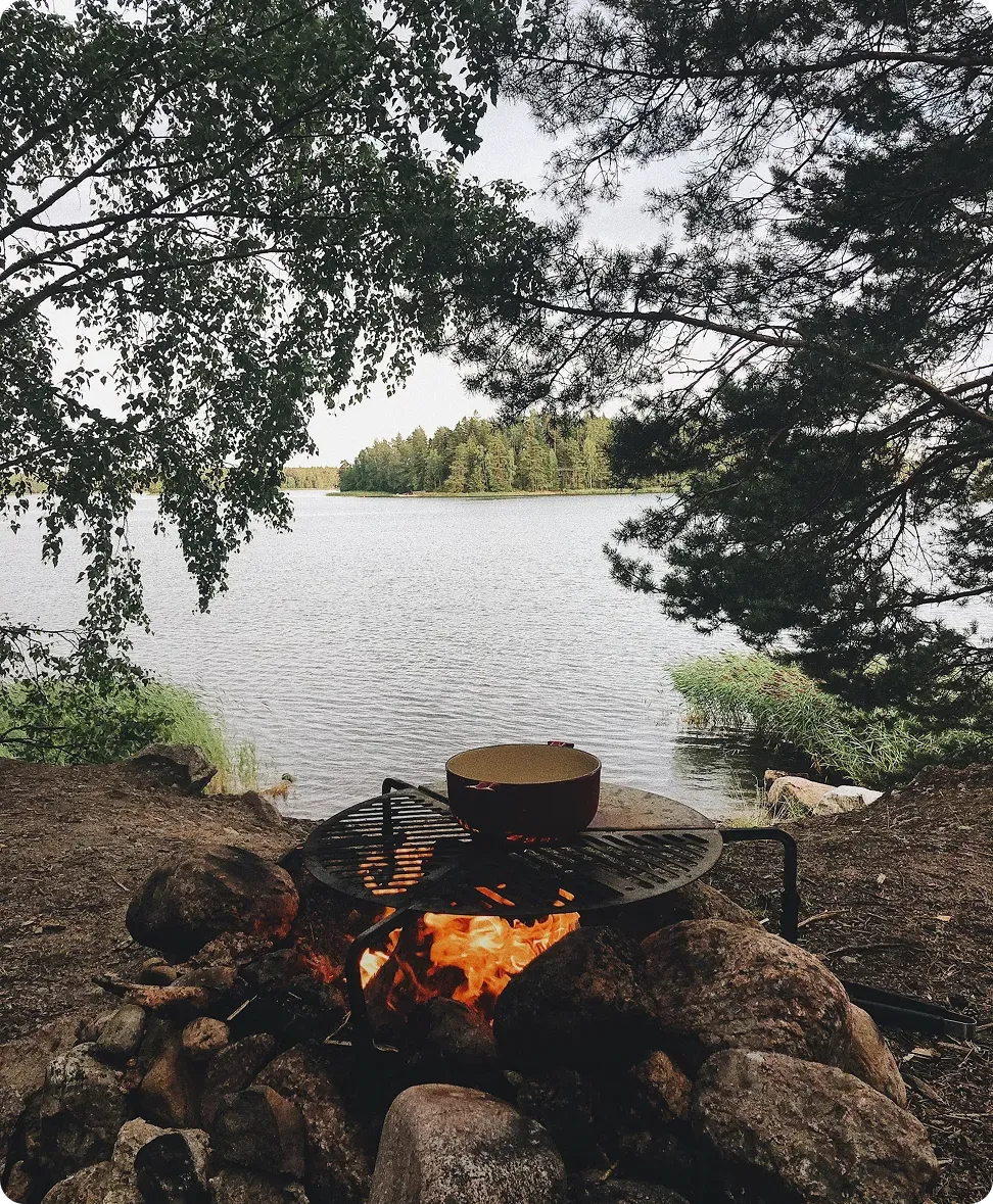 Lagerfeuer an einem von Wald umgebenen See.