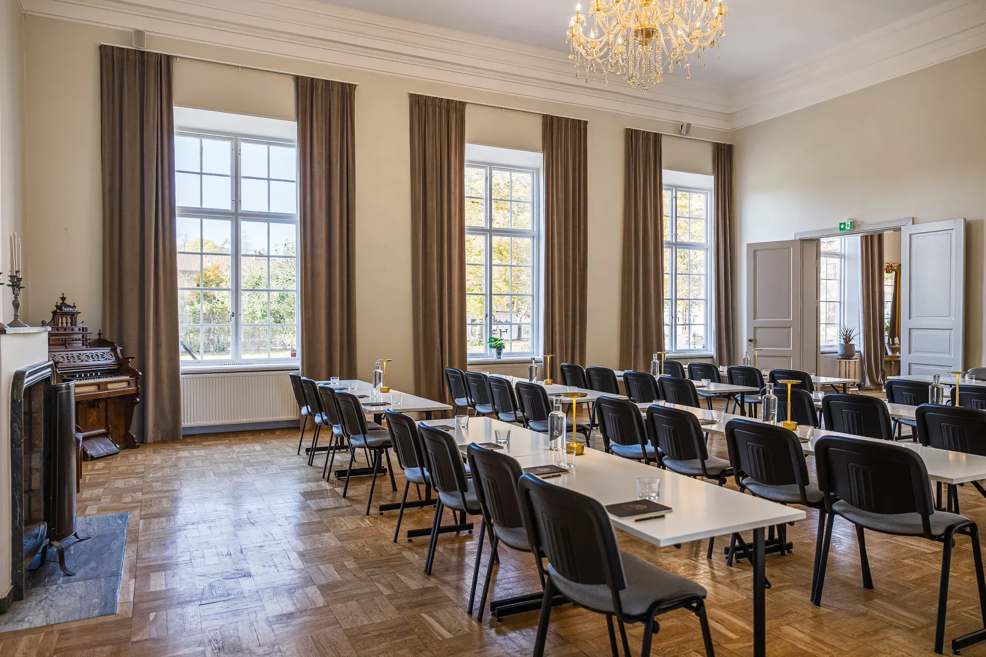 Ankarström in Klassenzimmeranordnung unter Kristallleuchtern.