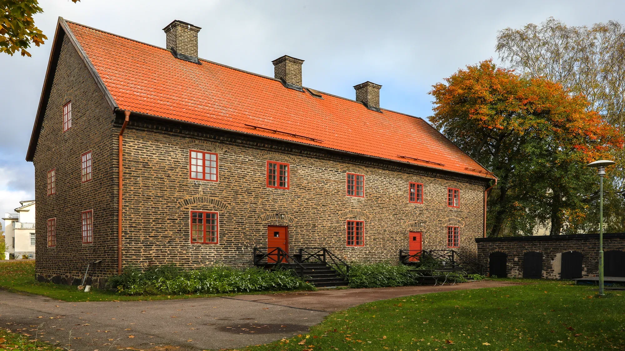 The dark-brick Widows' House with a red roof and red windows.